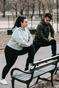 Young obese female with ethnic male instructor exercising together in park