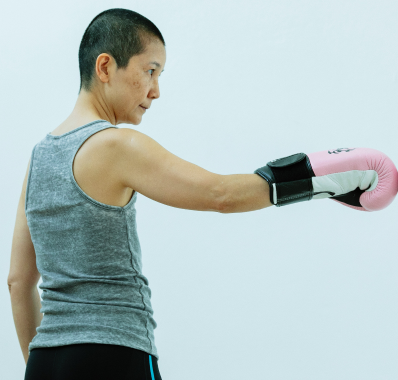 Serious Asian lady in pink boxing gloves in studio