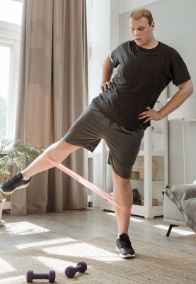 Man in Black T-Shirt and Gray Shorts Doing Leg Exercises with Rubber Strength Band